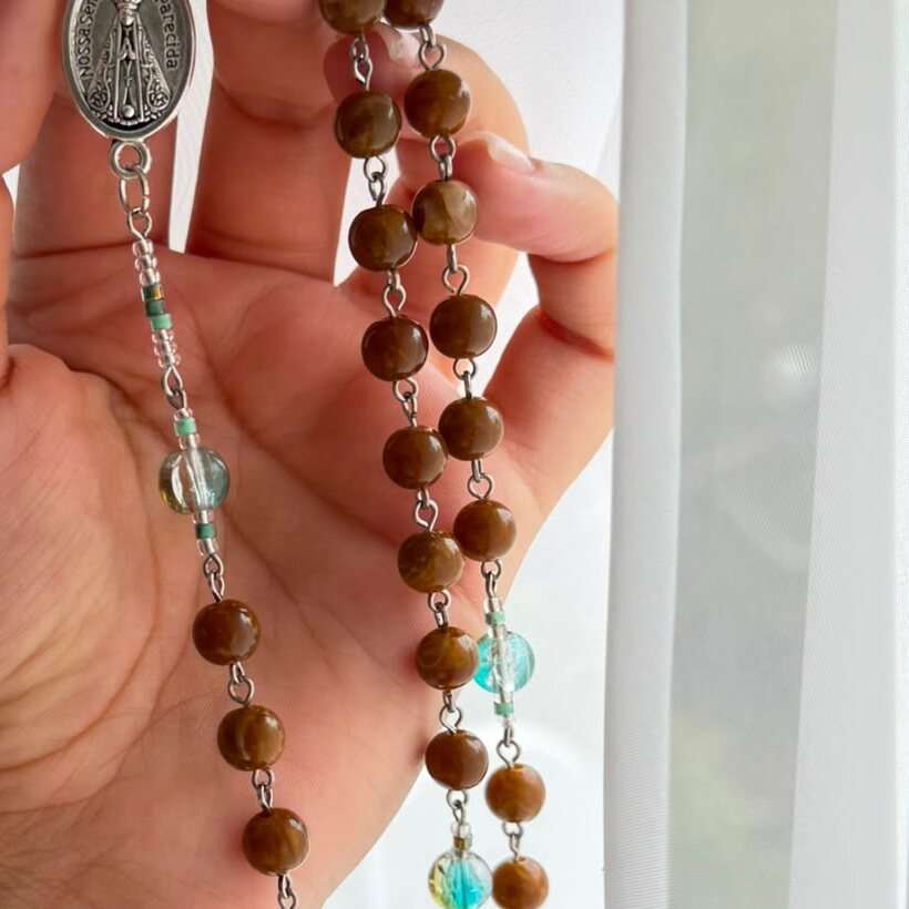 Close detail of the brown beads, each one differently marbled, seated on fine wire links with small green spacers between them