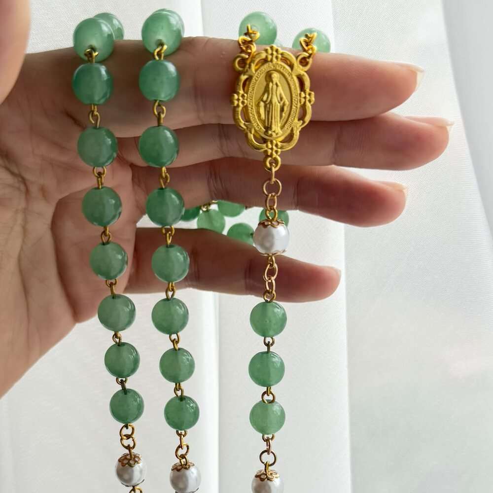 Close detail of bright green beads seated on hand-turned links, three lines of them falling past a worked oval centre